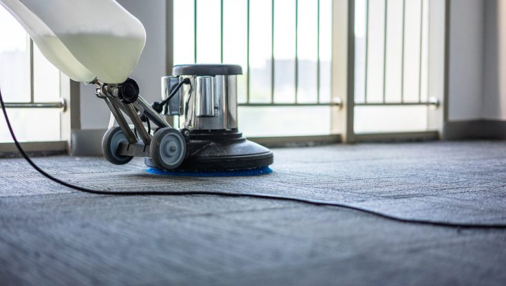 Ein professioneller Reiniger arbeitet an einem Teppich, während er eine leistungsstarke Reinigungsmaschine verwendet, um hartnäckigen Schmutz zu entfernen. Der Teppich erstrahlt nach der Reinigung in frischem Glanz, frei von Flecken und Verschmutzungen.